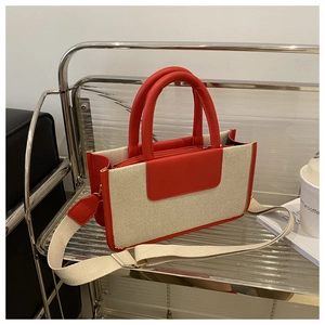 Detail of red and cream canvas tote bag with a wide adjustable shoulder strap and leather handles