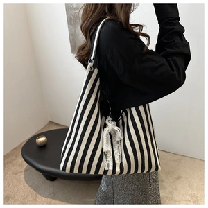 Detail of black and white striped tote bag with delicate white lace bow accessory