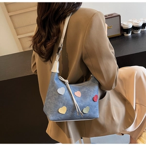 Blue denim underarm bag featuring colorful heart appliques and stylish silver hardware