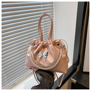 Détail du sac en satin rose avec papillon argenté et bandoulière en perles et chaîne