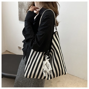 Detail of canvas tote bag with black and white stripes and white lace ribbon bow accent
