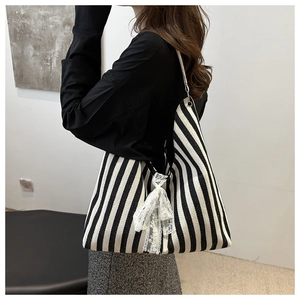 Detail view of large canvas tote with black and white stripes and delicate lace bow accent