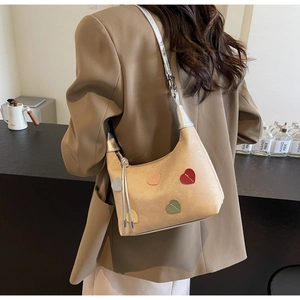 Detail view of heart-patterned half-moon shoulder bag with shiny silver metallic strap