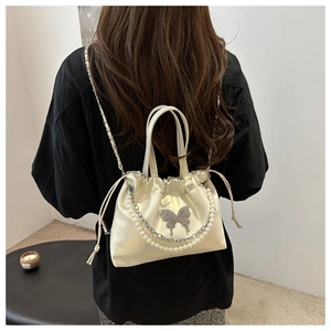 Détail du sac seau blanc cassé avec chaîne en perles et breloque papillon argentée