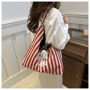 Detail of red and white striped canvas tote bag featuring a white lace bow decoration