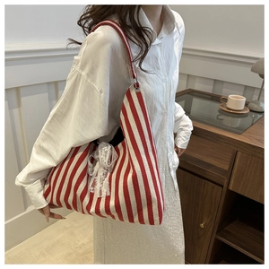 Detail shot of the red and white striped canvas tote bag featuring a white lace bow accent