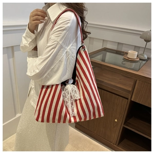 Detail of red and white striped canvas tote bag featuring a delicate white lace bow detail