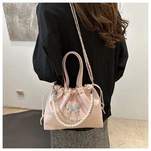 Détail du sac seau en satin rose avec boucle papillon et bandoulière en perles