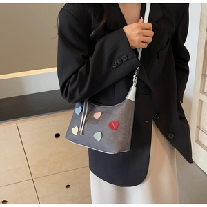 Detail of grey crossbody bag with colorful heart patches on a minimalist fashion model