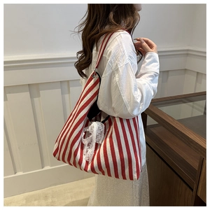 Detail of red and white striped canvas tote bag with a white lace bow decoration