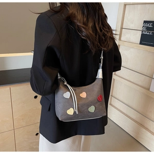 Detail of grey canvas shoulder bag with colorful heart patches on a female model