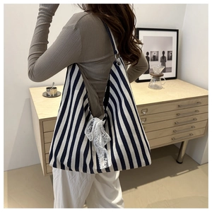 Detail of striped canvas tote bag with lace bow and adjustable ring strap on model