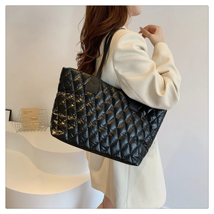 Close-up of black quilted tote bag with glossy finish and elegant shoulder straps