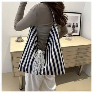 Detail of large canvas tote bag with navy blue vertical stripes and white lace bow