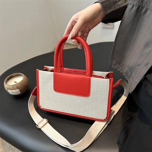 Chic woven tote bag with red leather trim and matching canvas shoulder strap