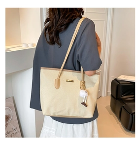 Détail d'un cabas tissé beige avec lanières en cuir marron et pendentif fleur