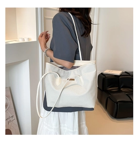 Vue détaillée du grand sac cabas blanc avec texture tissée et plaque logo en métal