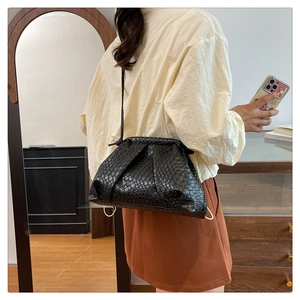 Detail of black woven cloud bag worn over the shoulder with thin strap and soft pleats