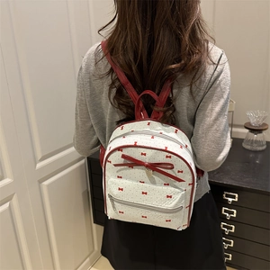 Zaino da donna bianco con motivi a fiocco rosso indossato da una modella
