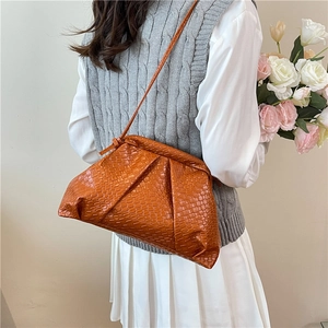 Brown pleated cloud bag with woven texture and crossbody strap in a minimalist setting