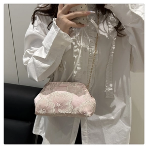 Detail of pink satin cosmetic bag with white floral embroidery and gold chain strap