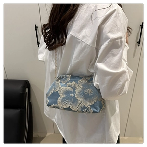 Detailed view of an elegant blue silk shell bag featuring vintage floral embroidery
