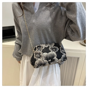 Detailed embroidery of white and gray flowers on a black fabric chain crossbody bag