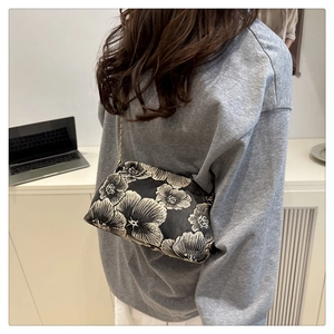 Close-up of vintage black shell bag with floral embroidery and golden chain strap