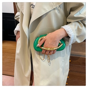 Détail du sac à main en cuir vert émeraude avec une poignée métallique dorée en forme de U