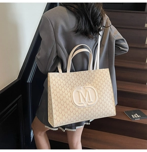 Detail of monogram pattern tote bag with embossed M logo and textured PU leather
