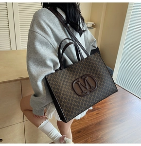 Grand sac cabas marron à motif monogramme et anses en cuir porté à l'épaule par un mannequin