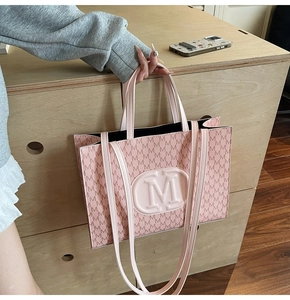 Gros plan du sac cabas rose avec imprimé monogramme M et logo en relief en PU