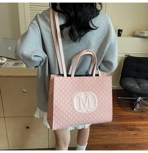 Detailed side view of pink tote bag with M-pattern print and long shoulder straps