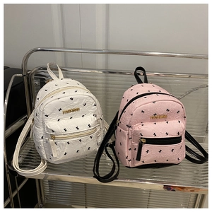 Detail of mini backpacks with black bow patterns and gold FASHION logos in white and pink