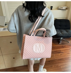 Détail du sac cabas rose avec motif à lettres M et logo en relief porté par le mannequin