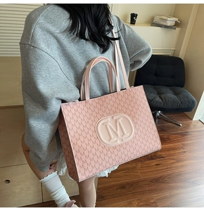 Detail shot of the pink M-pattern tote bag showing texture and logo on the shoulder strap
