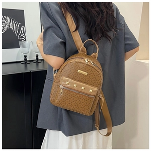 Détail d'un sac à dos en cuir marron avec monogramme, clous dorés et larges bretelles