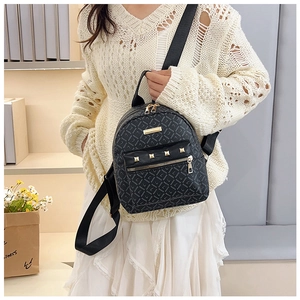 Détail du mini sac à dos noir avec logo imprimé, zips dorés et rivets carrés élégants
