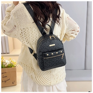 Vue lifestyle d'un mini sac à dos noir avec clous dorés et motifs de lettres répétés