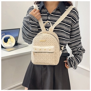 Détail d'un mini sac à dos en cuir PU beige avec imprimé lettres et clous dorés