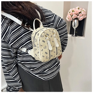 Détail d'un mini sac à dos beige avec imprimés d'ours et doubles fermetures éclair