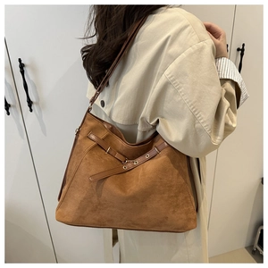 Brown suede tote bag side view on beige trench coat showing buckle and strap details