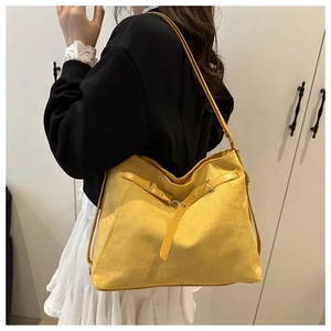 Detail of a bright yellow matte leather tote bag with stylish decorative belt buckle detail
