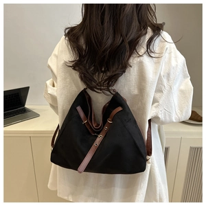 Minimalist black tote bag with brown leather straps shown on a model in a modern office