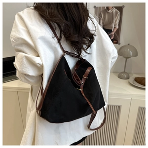 Detail of a black matte tote bag with brown leather straps and vintage metal buckles