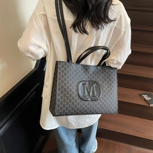 Grand sac cabas noir avec motif M et logo en relief vu sous un angle de vue élevé