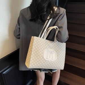 Sac fourre-tout tendance avec motif M et logo circulaire porté par un mannequin