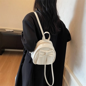 Elegant ivory faux leather mini backpack featuring a large bow and slim straps