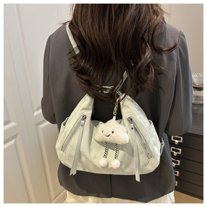 Mint green backpack detail with white fluffy cloud charm on a model back view