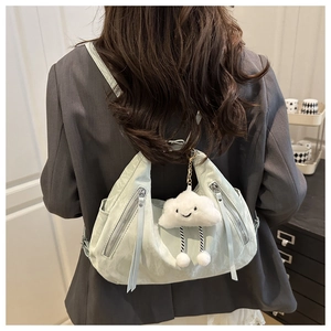 Detail of mint green crescent backpack with pleated texture and white cloud plush charm